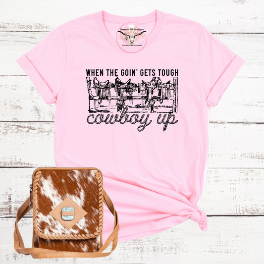 pink short sleeve tee with sublimation graphic design. Saddles on a fence reading When the goin gets tough cowboy up
